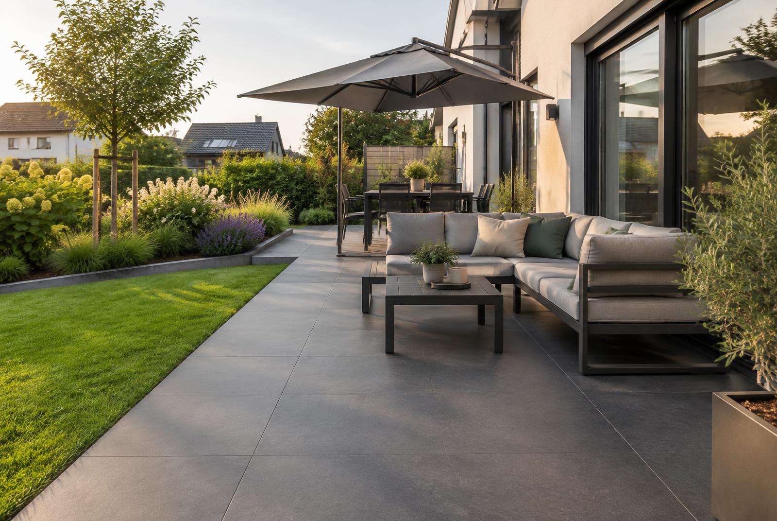 Fertige Terrasse mit großen anthrazitfarbenen Platten an einem Wohnhaus